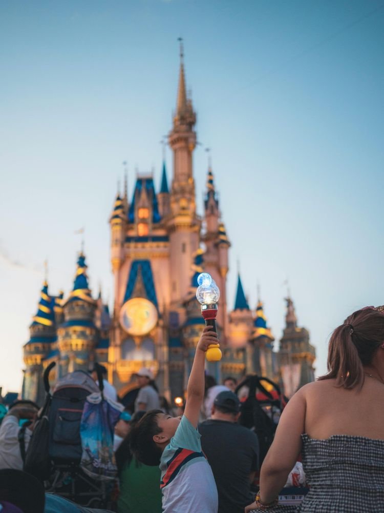 Atrações da Disney para Crianças de 2 Anos. Criança se divertindo em meio a multidão na frente do castelo do Magic Kingdom.